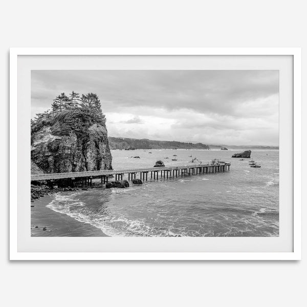 Scenic Pacific Northwest wall art of Trinidad State Park in California in black and white, showcasing a coastal pier, lush green cliffs, and calm ocean waves under cloudy skies.
