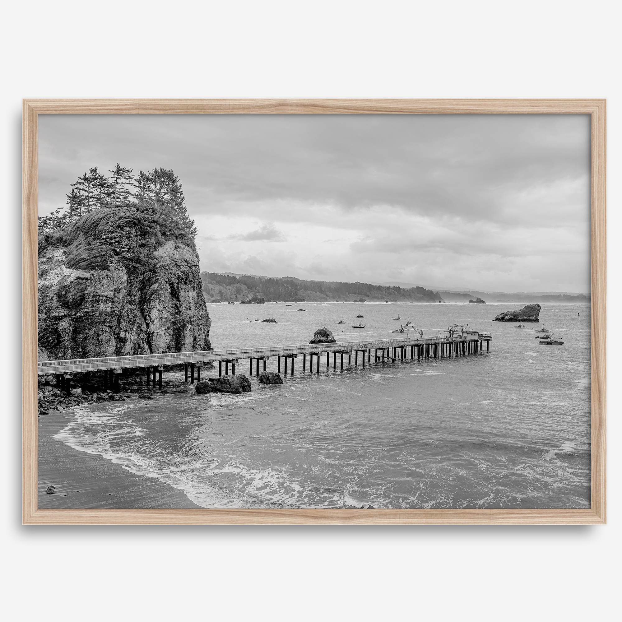 Scenic Pacific Northwest wall art of Trinidad State Park in California in black and white, showcasing a coastal pier, lush green cliffs, and calm ocean waves under cloudy skies.