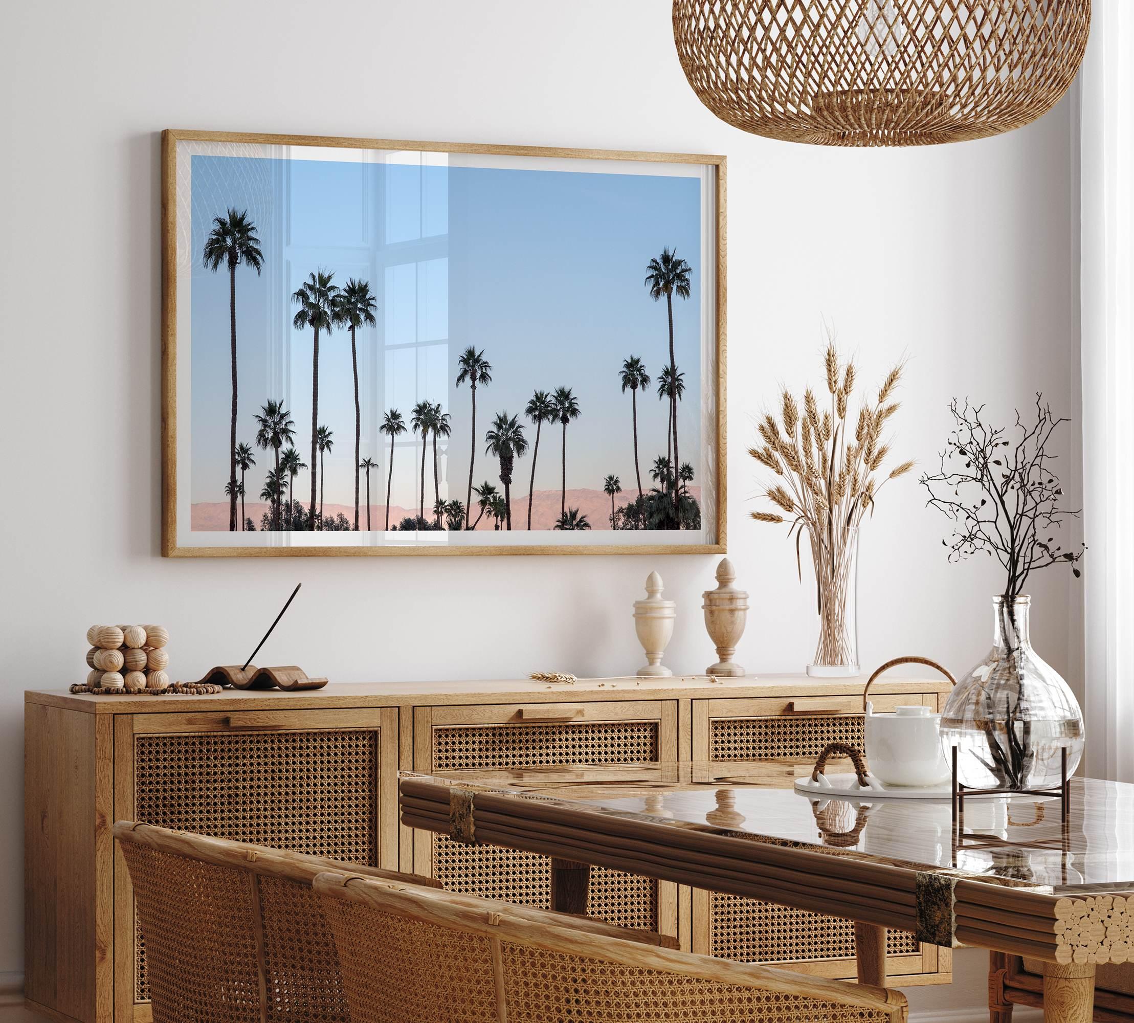 Silhouetted palm trees in Palm Springs under a clear blue sky with pink desert mountains in background