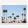 Silhouetted palm trees in Palm Springs under a clear blue sky with pink desert mountains in background