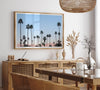 Silhouetted palm trees in Palm Springs under a clear blue sky with pink desert mountains in background