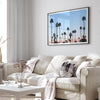 Silhouetted palm trees in Palm Springs under a clear blue sky with pink desert mountains in background