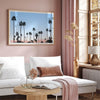 Silhouetted palm trees in Palm Springs under a clear blue sky with pink desert mountains in background