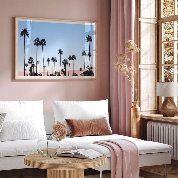 Silhouetted palm trees in Palm Springs under a clear blue sky with pink desert mountains in background