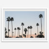 Silhouetted palm trees in Palm Springs under a clear blue sky with pink desert mountains in background