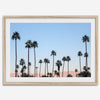 Silhouetted palm trees in Palm Springs under a clear blue sky with pink desert mountains in background