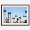 Silhouetted palm trees in Palm Springs under a clear blue sky with pink desert mountains in background