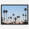 Silhouetted palm trees in Palm Springs under a clear blue sky with pink desert mountains in background