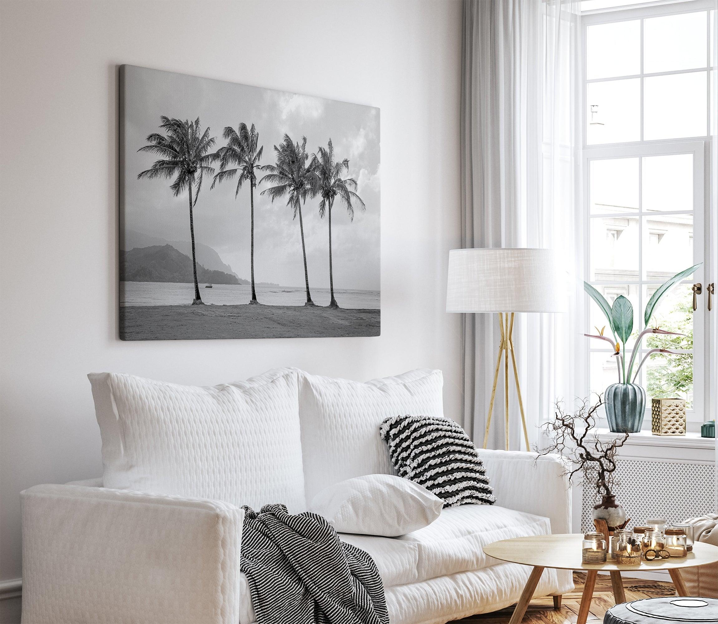 Black and white canvas print of four tall palm trees on Hanalei Bay beach in Kauai, with mountains and cloudy sky in the background.