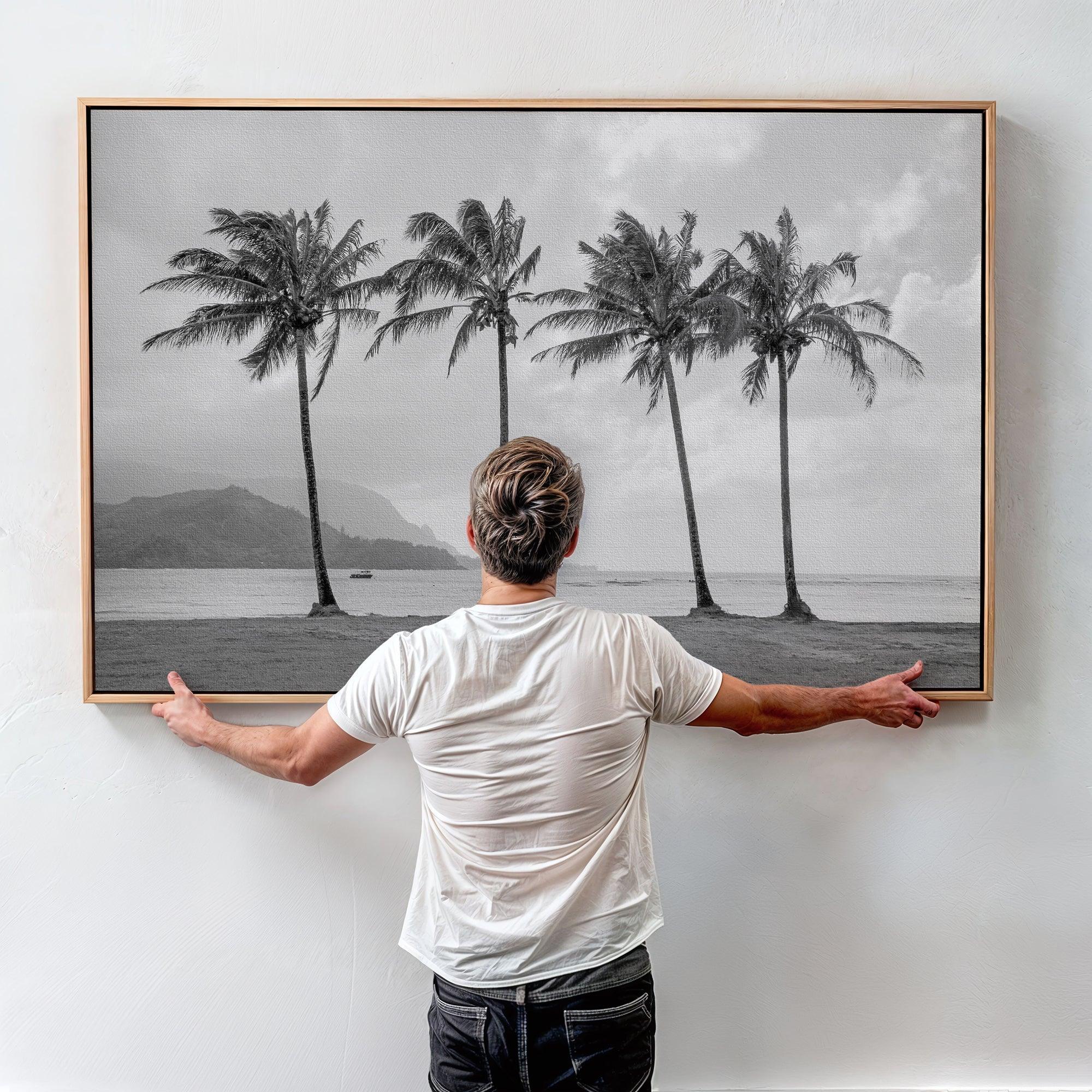 Black and white canvas print of four tall palm trees on Hanalei Bay beach in Kauai, with mountains and cloudy sky in the background.