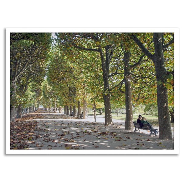 A fine art Paris print of Jardin des Tuileries in fall, featuring a couple sitting on a bench beneath vibrant autumn trees, surrounded by golden foliage.