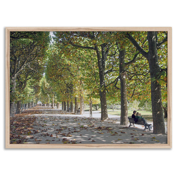 A fine art Paris print of Jardin des Tuileries in fall, featuring a couple sitting on a bench beneath vibrant autumn trees, surrounded by golden foliage.