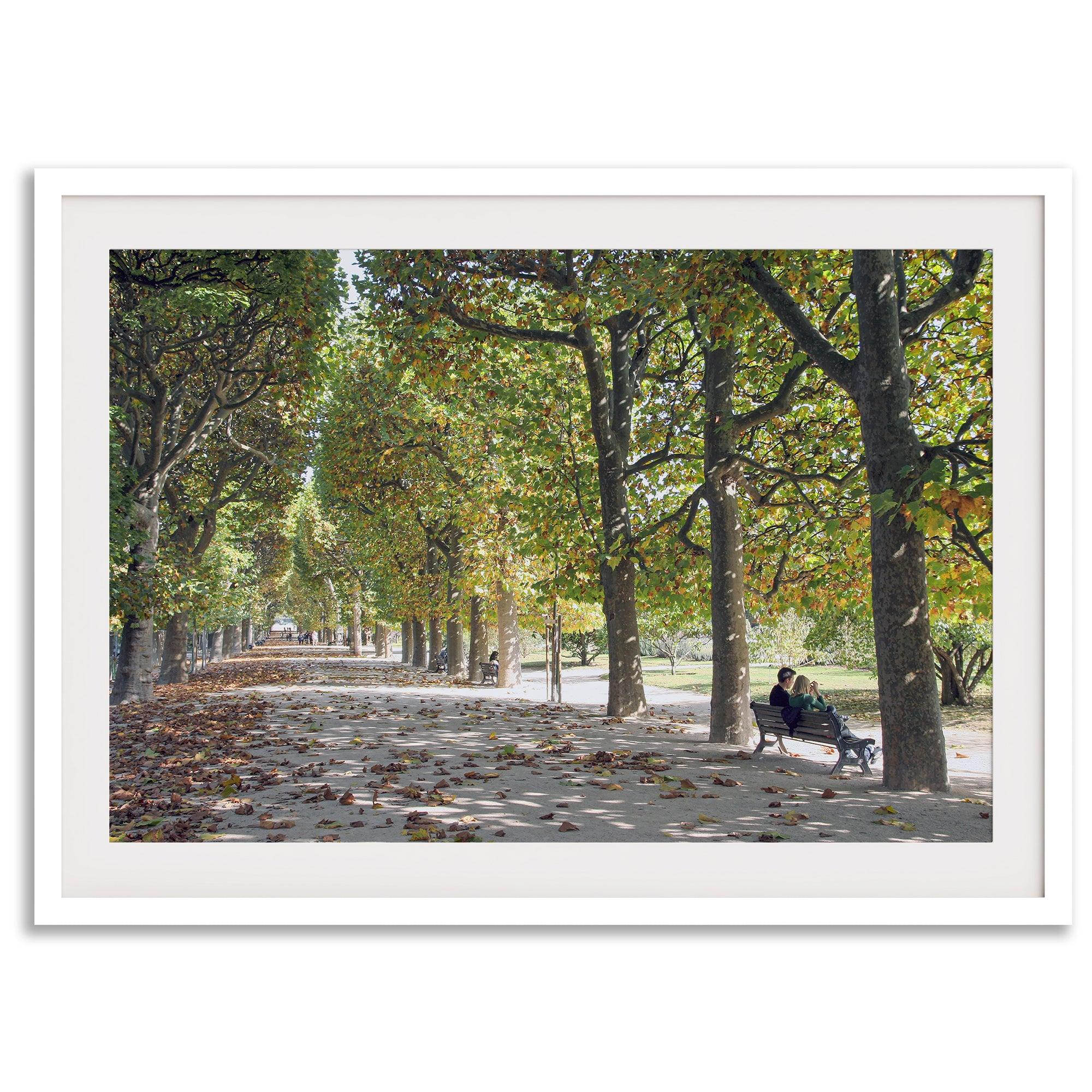 A fine art Paris print of Jardin des Tuileries in fall, featuring a couple sitting on a bench beneath vibrant autumn trees, surrounded by golden foliage.