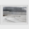 This fine art ocean photography print was taken in Pismo Beach, California, and showcases a distant view of an ocean pier and stormy clouds. Looking long and hard, you can see tens of surfers around the pier.