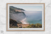 A fine art print of a misty beach in Big Sur, California. Waves crash against the shore as fog drapes over the rugged coastal cliffs, creating a serene, atmospheric scene