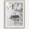 Monochrome ski lift view from below with hanging skis and cloudy mountain sky background.