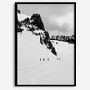 A fine art print showing five skiers traversing a vast, snowy mountain landscape under a pale winter sky, surrounded by untouched wilderness.