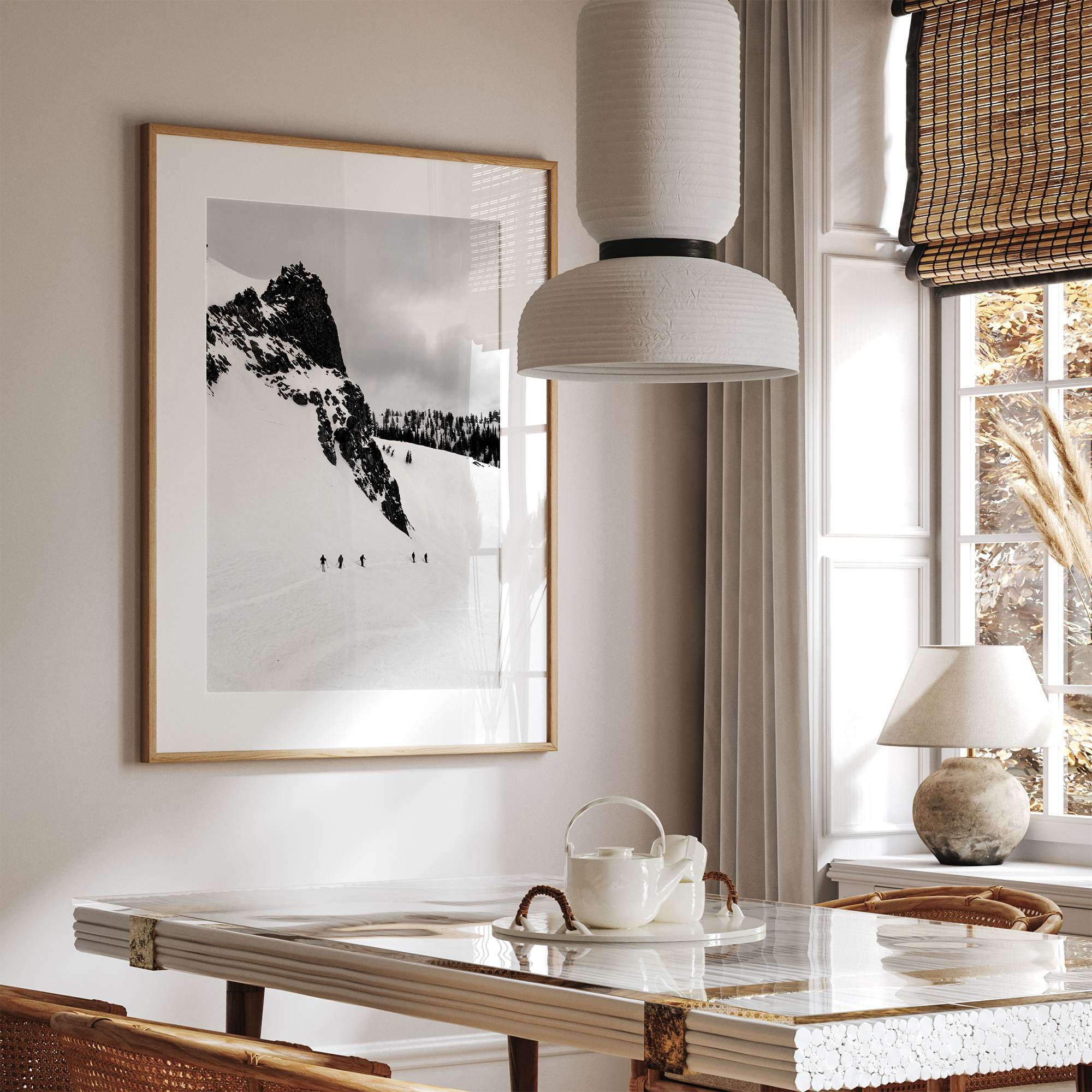 A fine art print showing five skiers traversing a vast, snowy mountain landscape under a pale winter sky, surrounded by untouched wilderness.