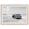 Black and white vintage beach print featuring a classic car parked at the edge of the ocean, capturing a retro coastal scene with timeless charm.