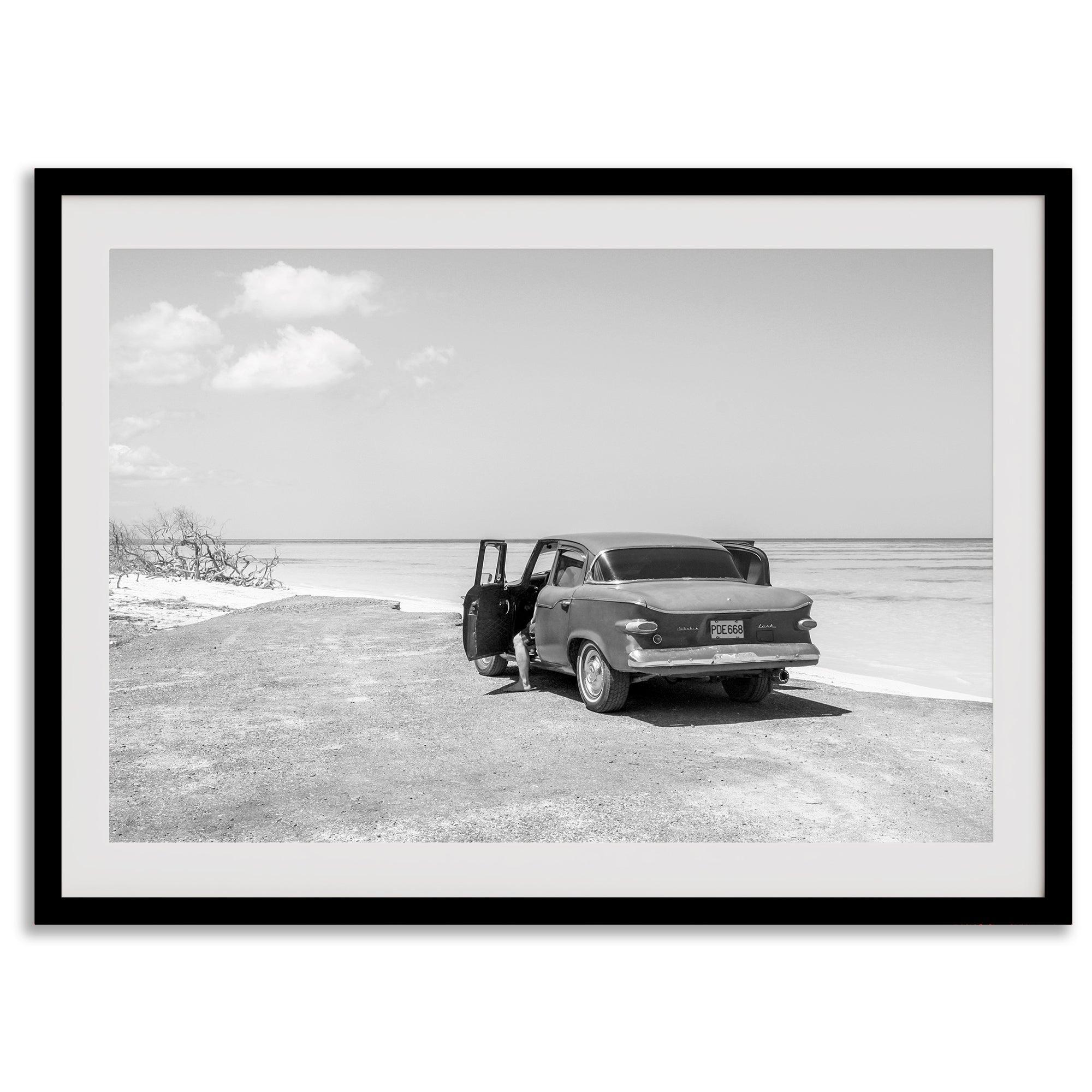 Black and white vintage beach print featuring a classic car parked at the edge of the ocean, capturing a retro coastal scene with timeless charm.