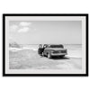 Black and white vintage beach print featuring a classic car parked at the edge of the ocean, capturing a retro coastal scene with timeless charm.