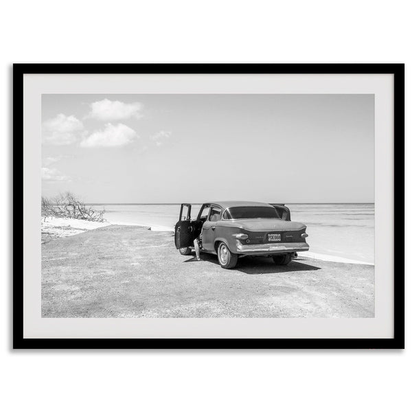 Black and white vintage beach print featuring a classic car parked at the edge of the ocean, capturing a retro coastal scene with timeless charm.