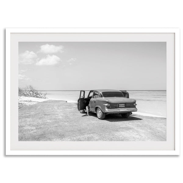 Black and white vintage beach print featuring a classic car parked at the edge of the ocean, capturing a retro coastal scene with timeless charm.