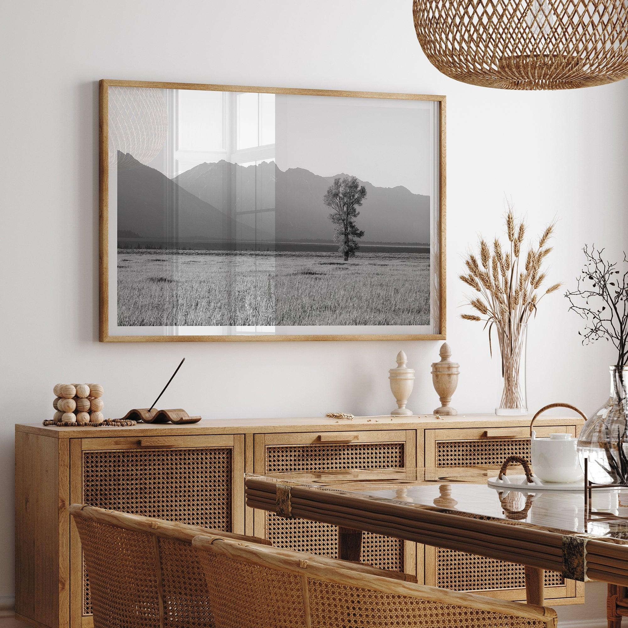 Lone tree in a peaceful field with Grand Teton mountains in the distance, black and white landscape art.