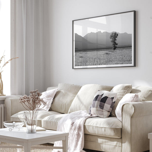 Lone tree in a peaceful field with Grand Teton mountains in the distance, black and white landscape art.