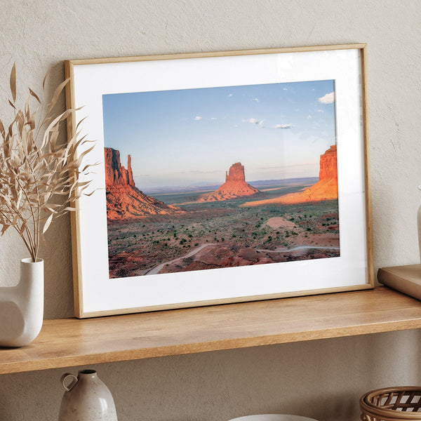 A fine art landscape photography print of a desert sunset over Monument Valley, located on the Arizona-Utah border. The warm and vibrant hues of this American Southwest sunset create a mesmerizing and awe-inspiring scene.