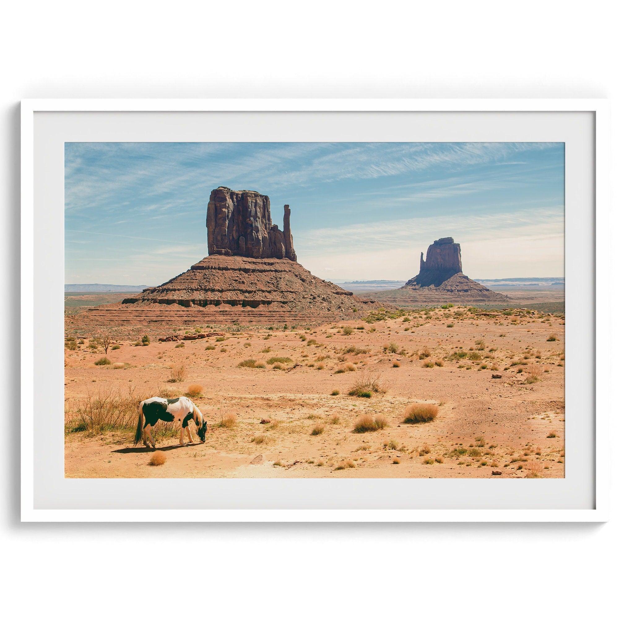 A framed or unframed fine art photography desert print of a horse in Monument Valley, Utah. This wall art features unique rock formations native to the Monument Valley area. This horse wall art comes in different sizes, including extra large.