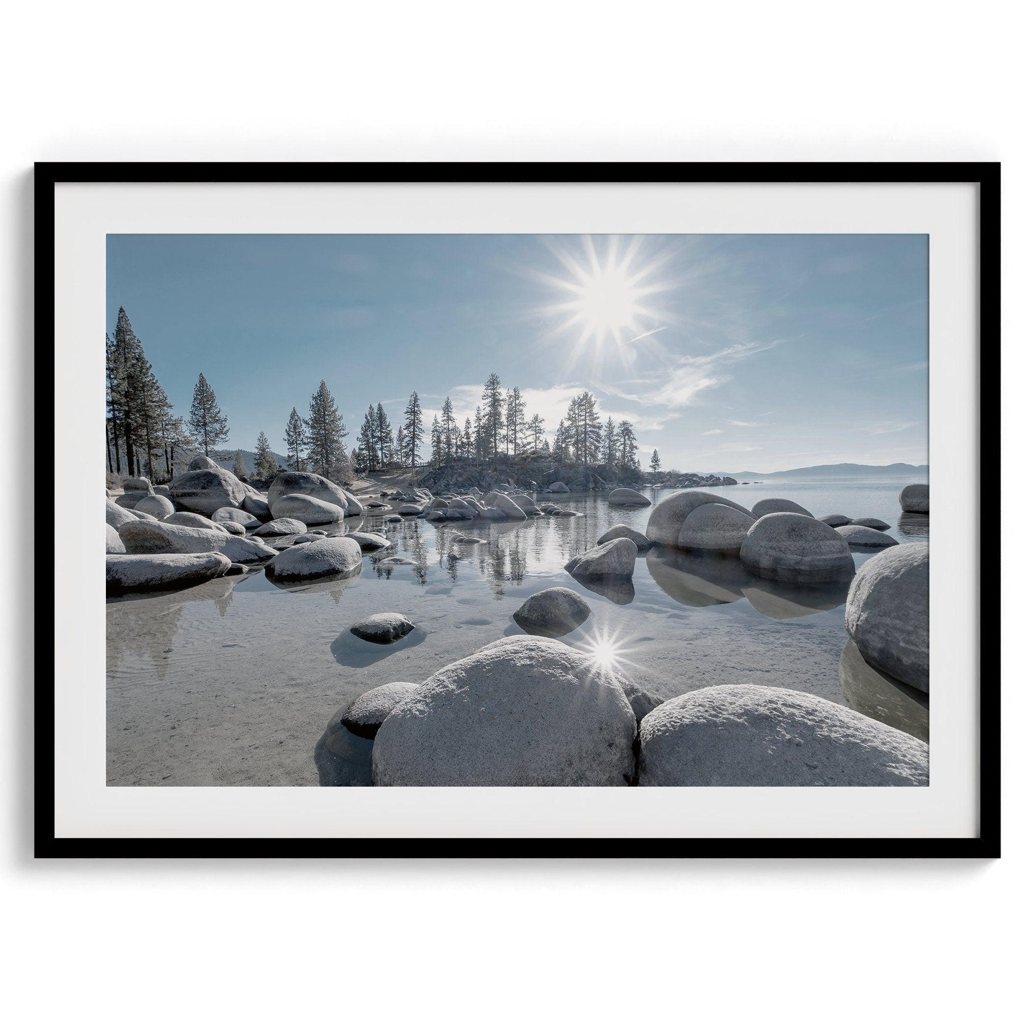 Capture the beauty of Lake Tahoe with this stunning lake wall art. The image showcases majestic rocks rising from crystal-clear water, contrasting with the blue sky. The sun's reflection adds a warm, magical touch to the breathtaking scenery.