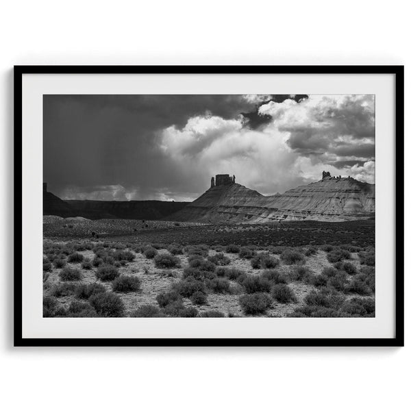 A fine art black and white desert photography print showcasing stunning rock formations, dramatic clouds, and desert plantation. Inspired by Ansel Adams.