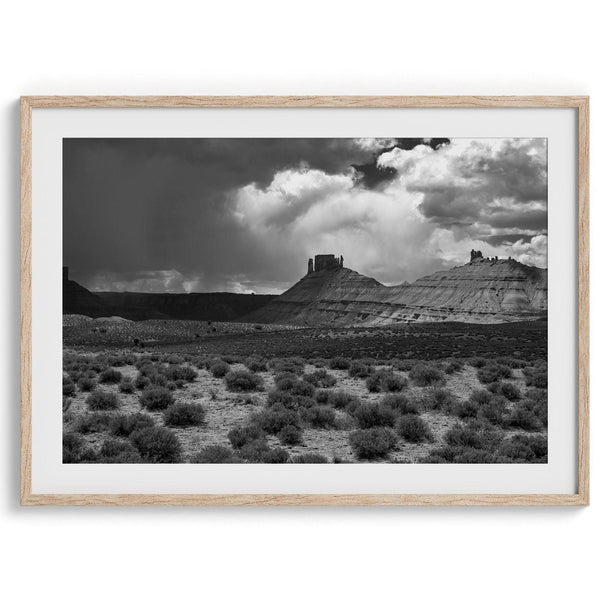 A fine art black and white desert photography print showcasing stunning rock formations, dramatic clouds, and desert plantation. Inspired by Ansel Adams.