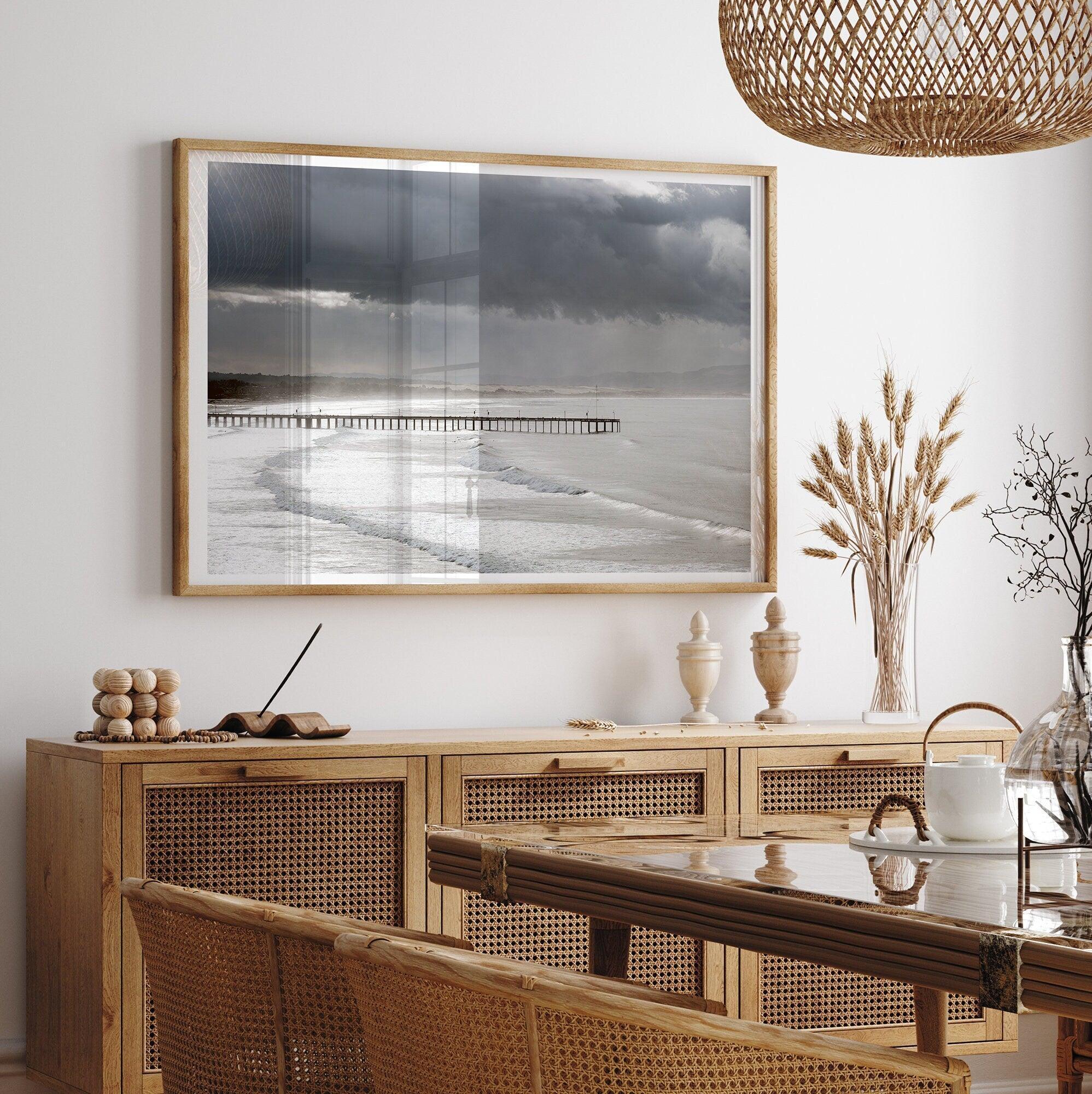 This fine art ocean photography print was taken in Pismo Beach, California, and showcases a distant view of an ocean pier and stormy clouds. Looking long and hard, you can see tens of surfers around the pier.