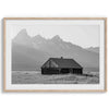 Step into Grand Teton National Park with this fine art black and white mountain print. This western landscape photo showcases a century-old rustic hut at the foot of the snowy, pointy Teton mountains.