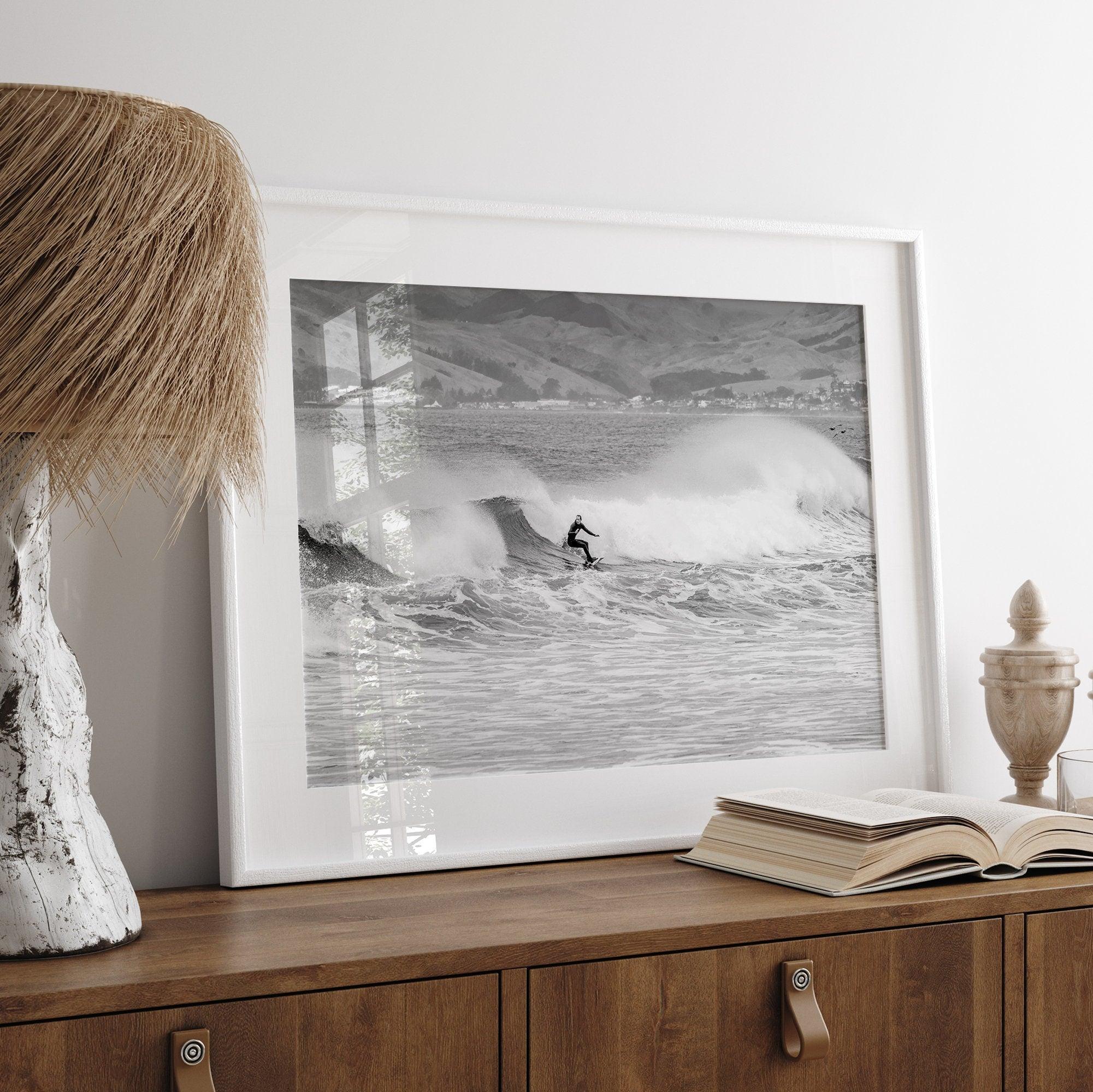 A black and white fine art surf print. This ocean wall art showcases a lone surfer riding the waves in Pismo Beach, California.