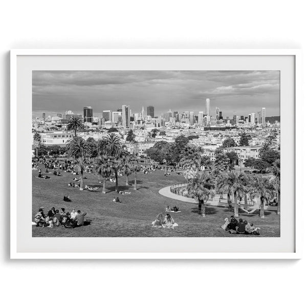 Black and white fine art print of Mission Dolores Park in San Francisco showcasing picnic blankets and people enjoying a quiet afternoon with the city skyline in the backdrop.