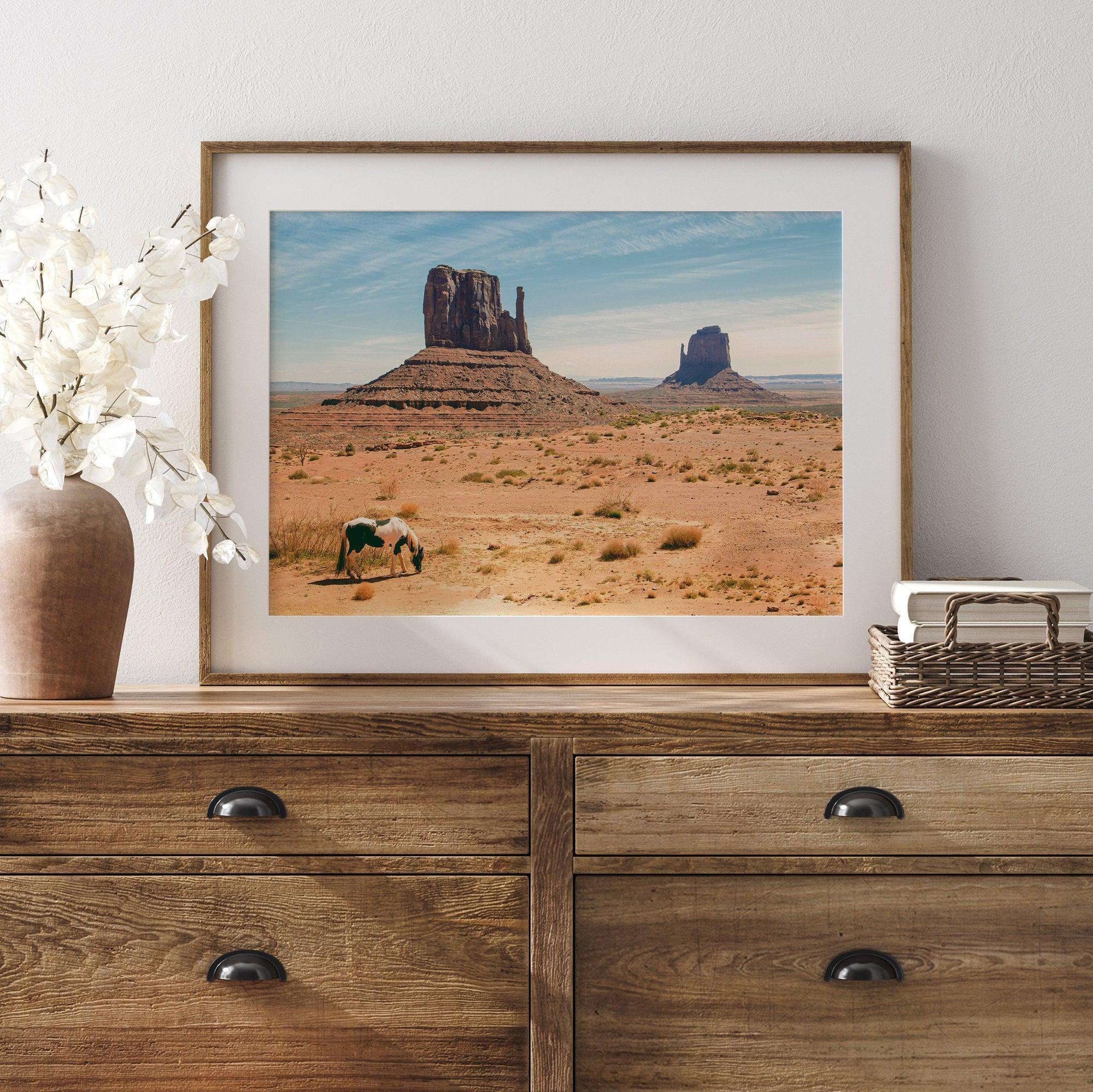 A framed or unframed fine art photography desert print of a horse in Monument Valley, Utah. This wall art features unique rock formations native to the Monument Valley area. This horse wall art comes in different sizes, including extra large.