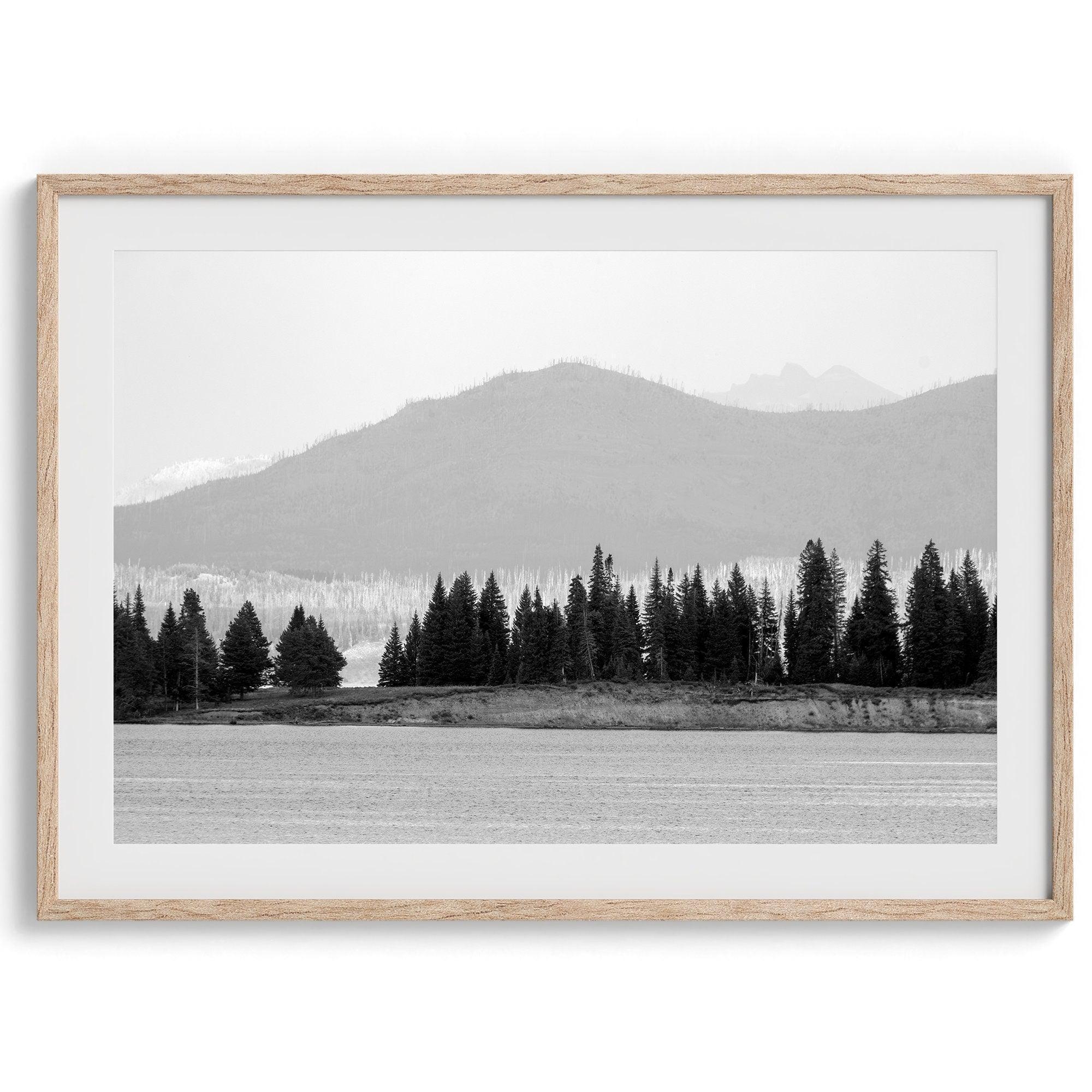 A black and white fine art print of a stunning forest island in the middle of Yellowstone Lake with towering faded mountains in the backdrop