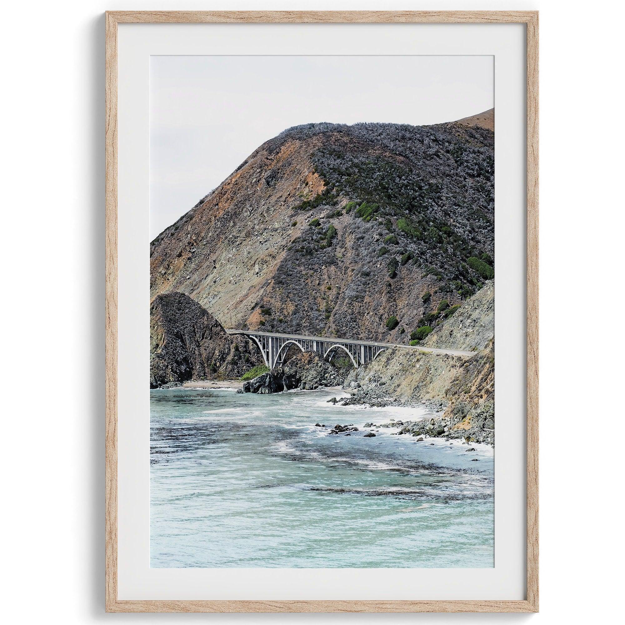 This California coastal print features the famous Bixby Bridge in Route 1, near Big Sur, In this Northwest Coast wall art you can see the ocean surf crashing against the coastal cliffs with the breathtaking old bridge in the center.