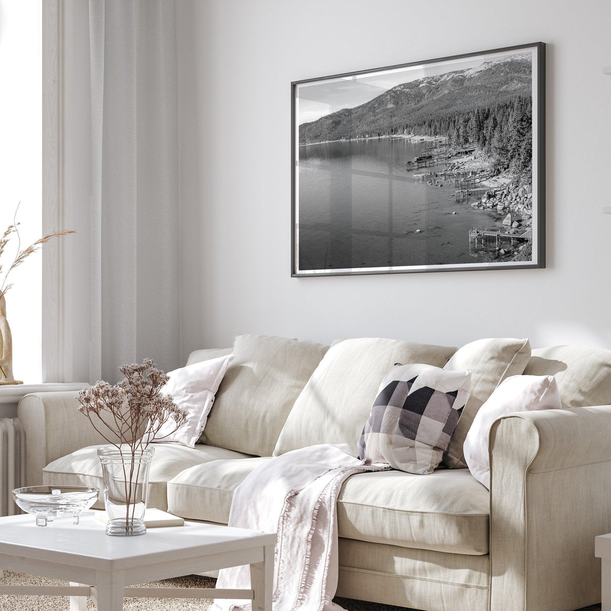 A fine art black and white Lake Tahoe print showcasing docks and boats nested on the lake waters on the left, while the beachfront, nestled against a backdrop of a lush forest and majestic mountain, paints a picturesque scene on the right.