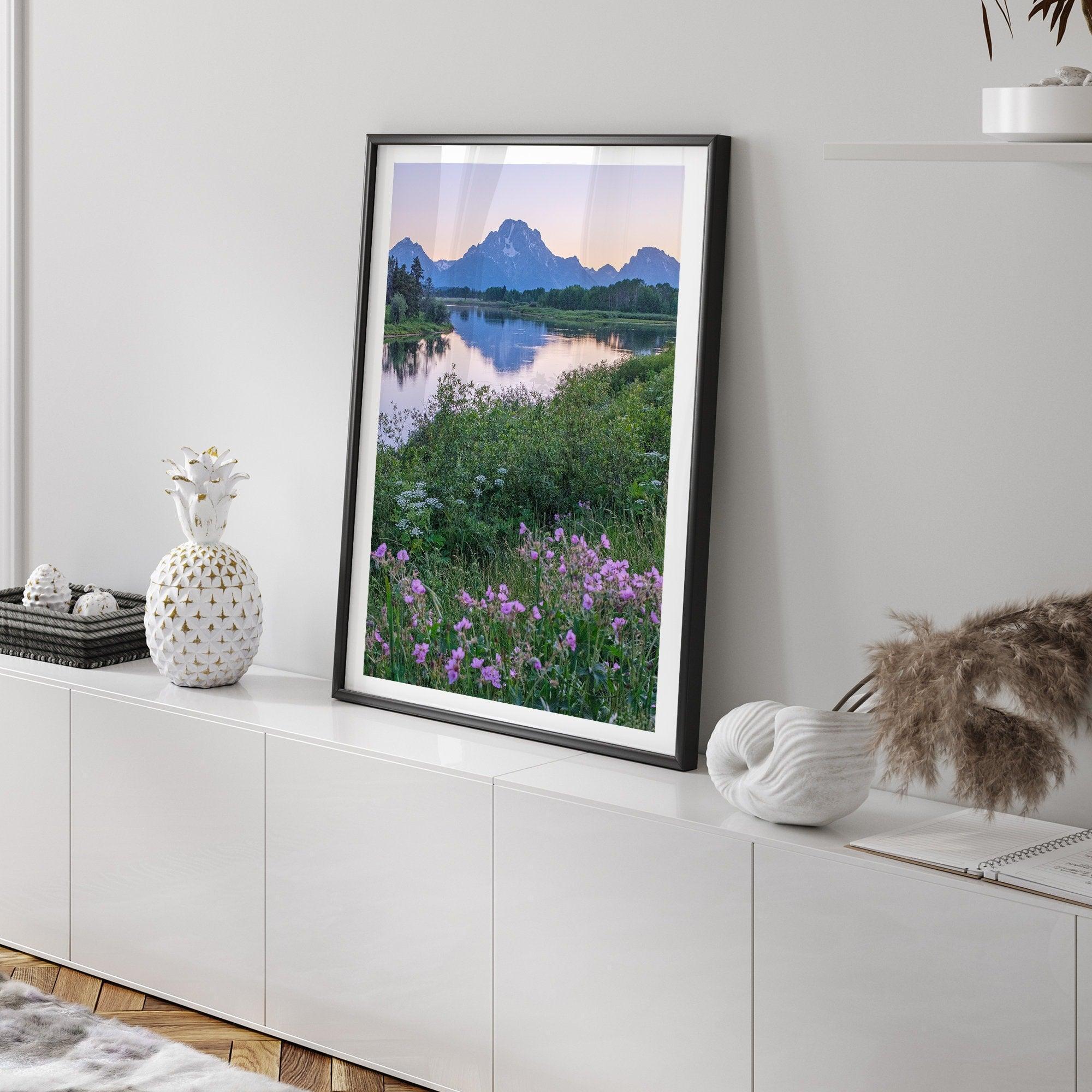 A fine art framed or unframed mountain print of Grand Teton National Park. This portrait orientation nature landscape wall art showcases the beautiful Teton mountains in a pink sunset, with Snake River and stunning flowers in the forefront.