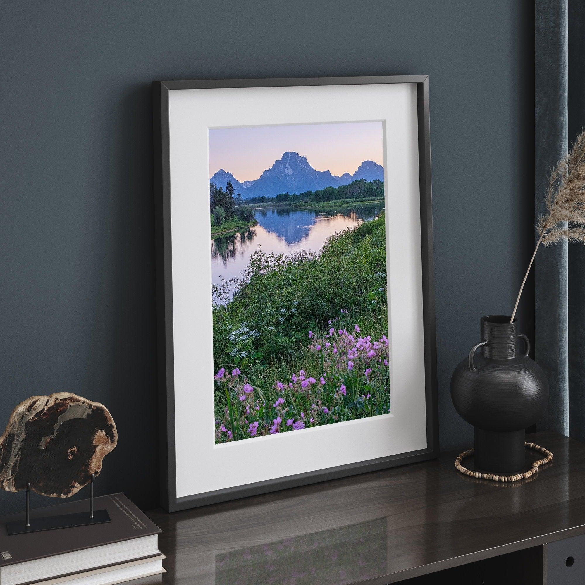 A fine art framed or unframed mountain print of Grand Teton National Park. This portrait orientation nature landscape wall art showcases the beautiful Teton mountains in a pink sunset, with Snake River and stunning flowers in the forefront.