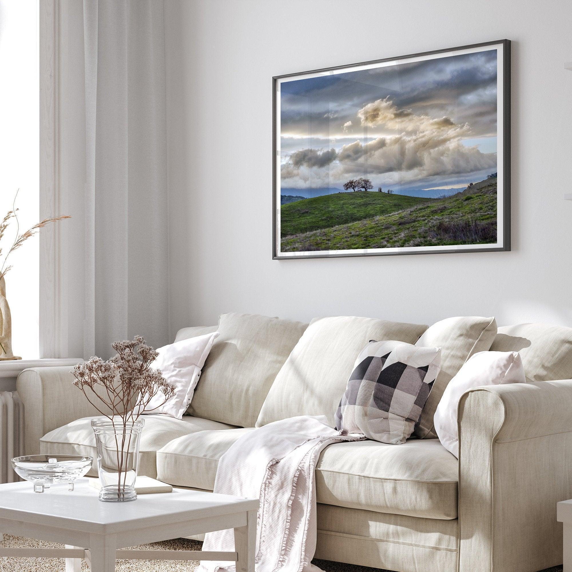 A fine art California moody landscape photography print showing a lone tree standing atop a hill against a dramatic cloudy sky in this scenic landscape wall art.