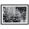 A fine art black and white photography print of a vibrant street in London during the Christmas holidays. This London wall art shows double-decker buses and black taxis, and the streets are adorned with bright holiday lights and festive decorations
