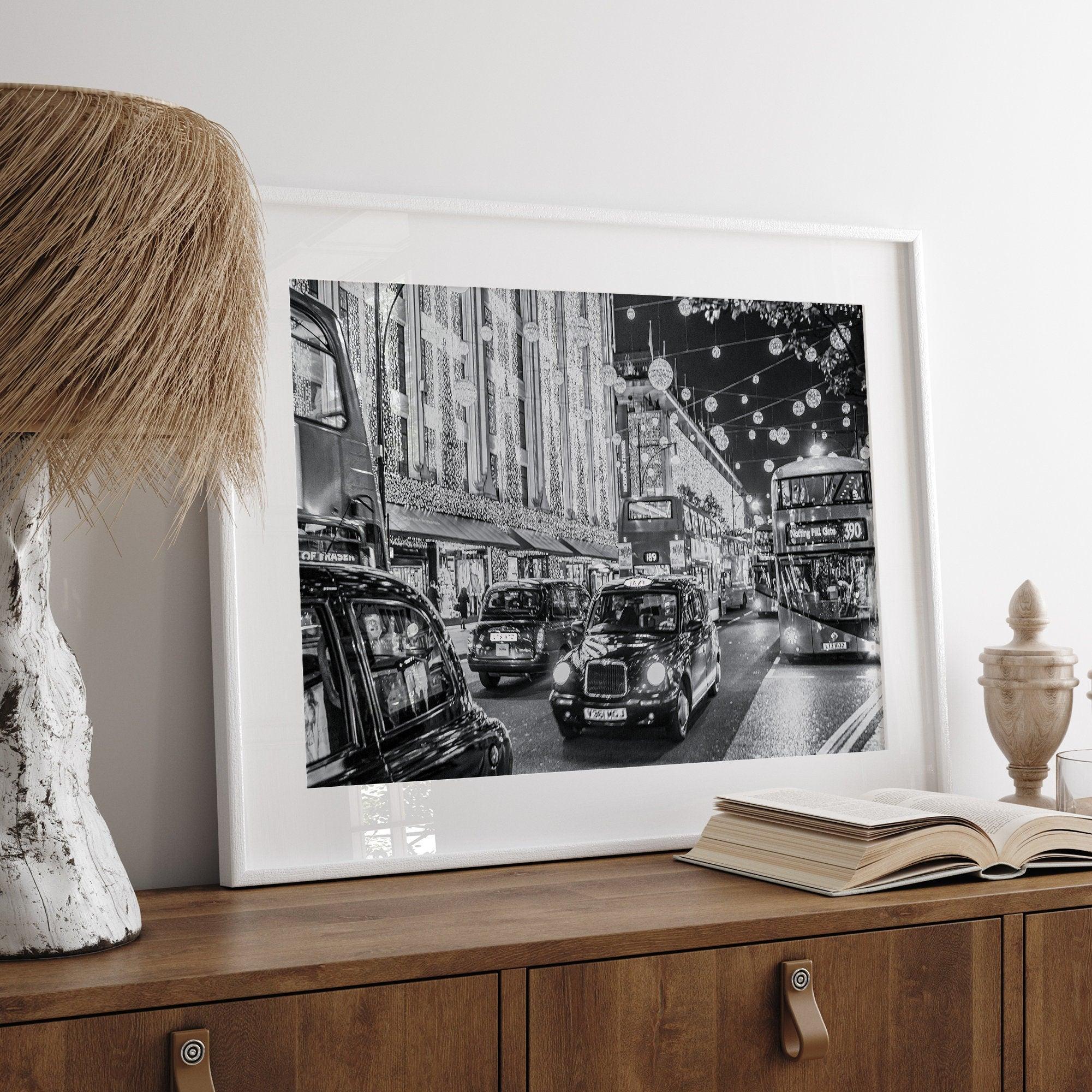 A fine art black and white photography print of a vibrant street in London during the Christmas holidays. This London wall art shows double-decker buses and black taxis, and the streets are adorned with bright holiday lights and festive decorations