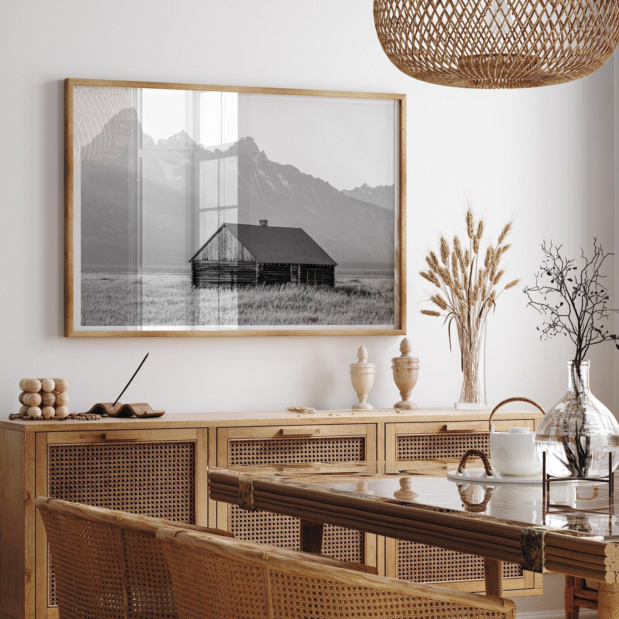 Step into Grand Teton National Park with this fine art black and white mountain print. This western landscape photo showcases a century-old rustic hut at the foot of the snowy, pointy Teton mountains.