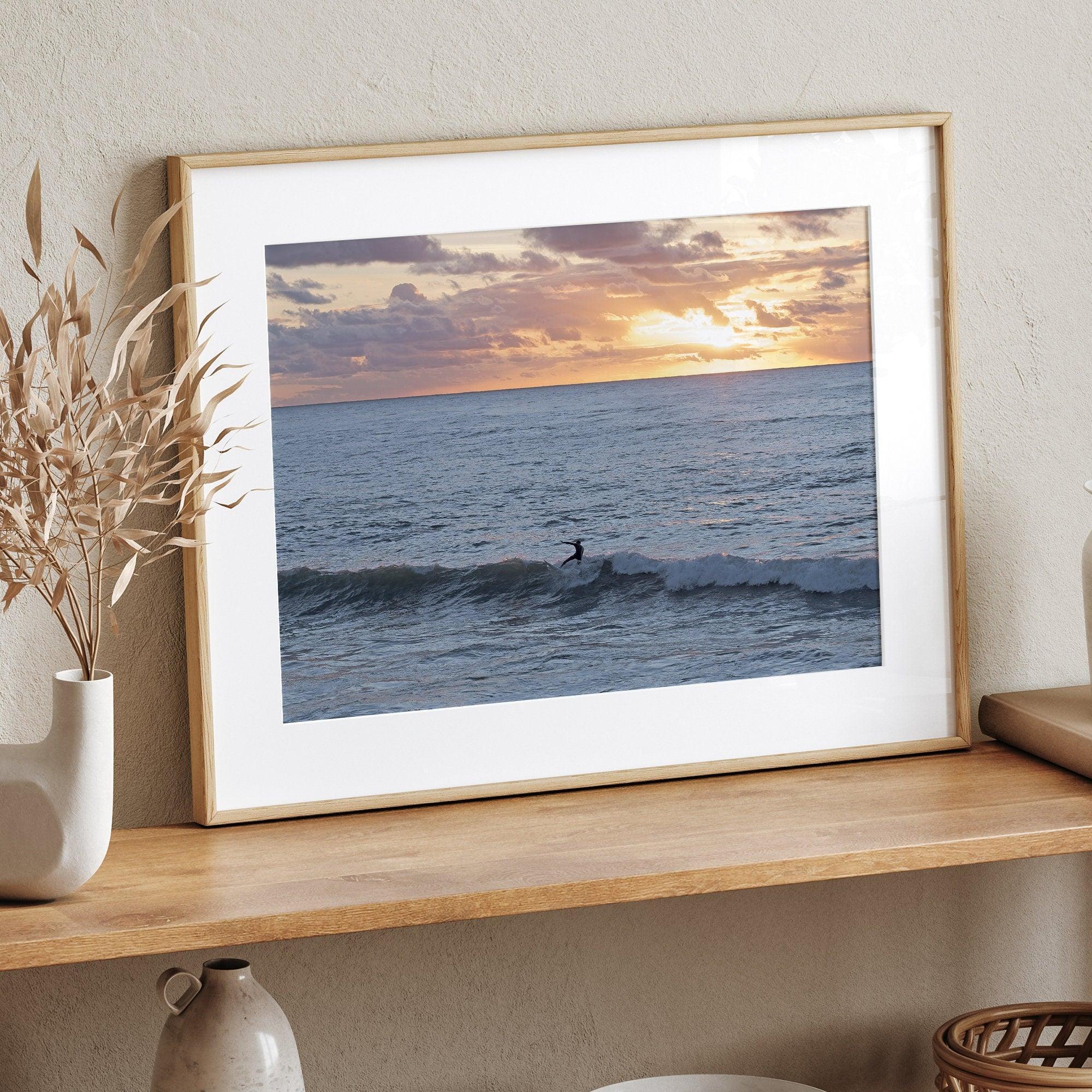 A fine art ocean sunset print showcasing a serene sunset and a lone surfer riding the waves. Taken in Montana De Oro State Park, California.