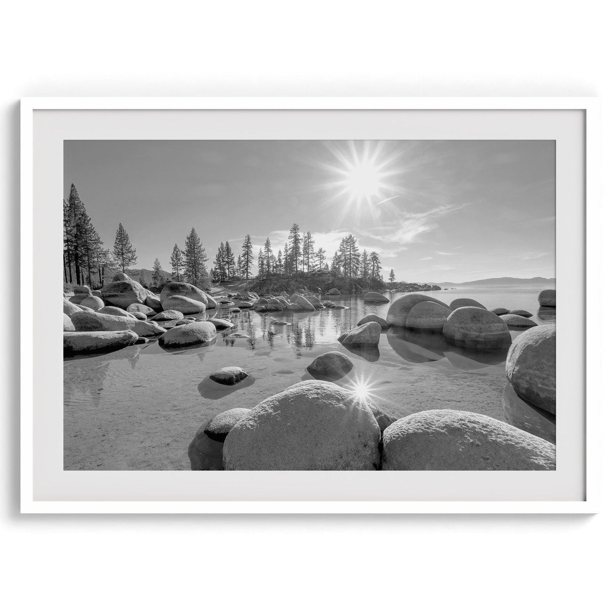 Capture the beauty of Lake Tahoe with this stunning black and white lake wall art. The image showcases majestic rocks rising from crystal-clear water. The reflection of the sun in the water adds a magical touch to the breathtaking scenery.